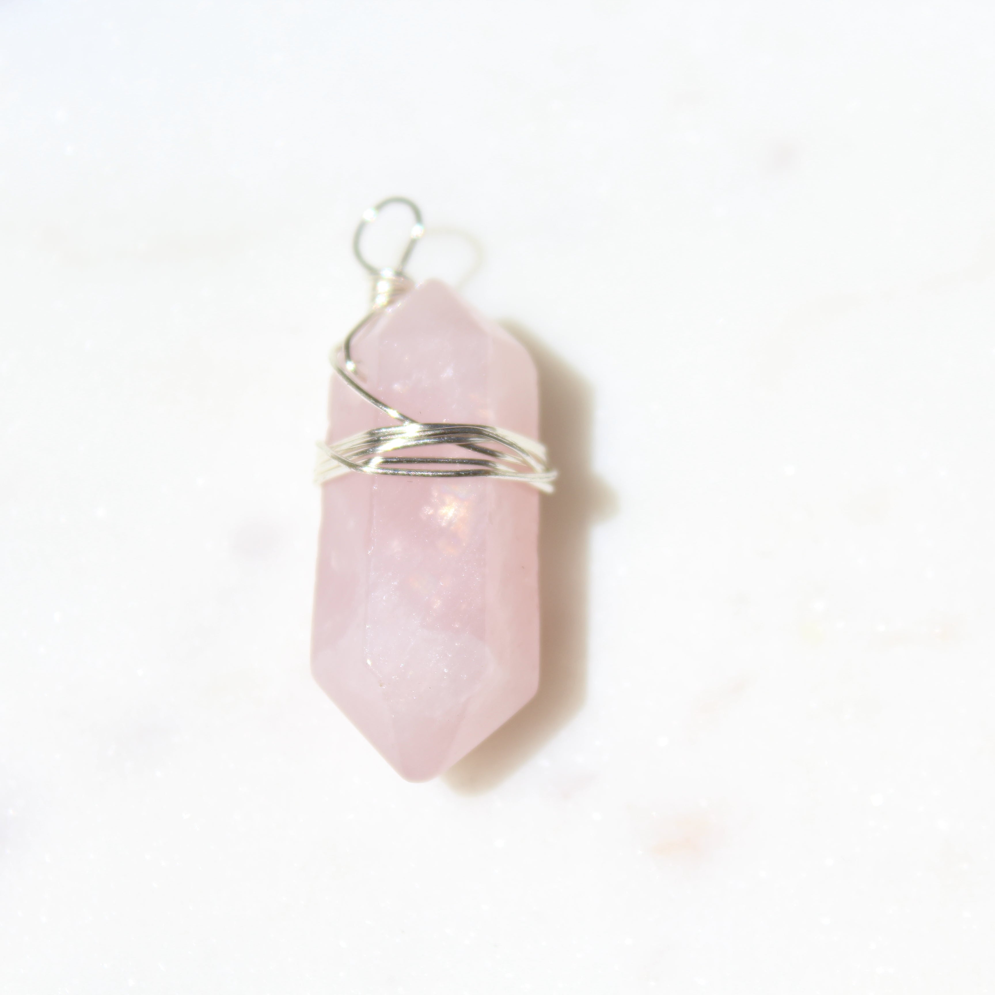 Pink crystal pendant with silver wire wrapping on a white background