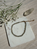 Bracelet on a marble coaster with flowers and a crystal